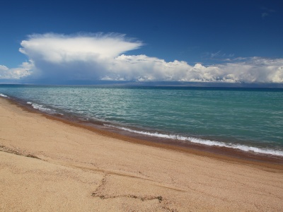 Snowy mountains and golden sands of Issyk Kul Lake
